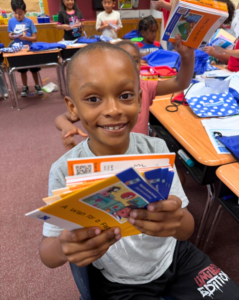 Student holding up his books, smiling for photo.