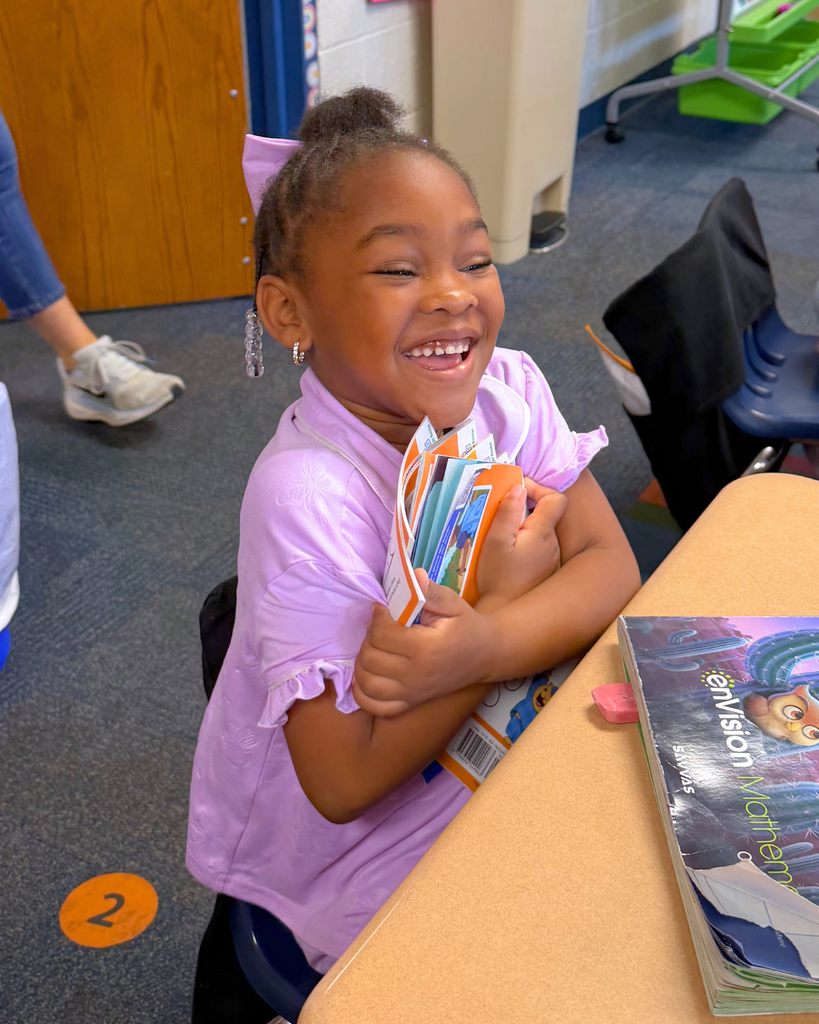 Student hugging her decodable books with a big smile.