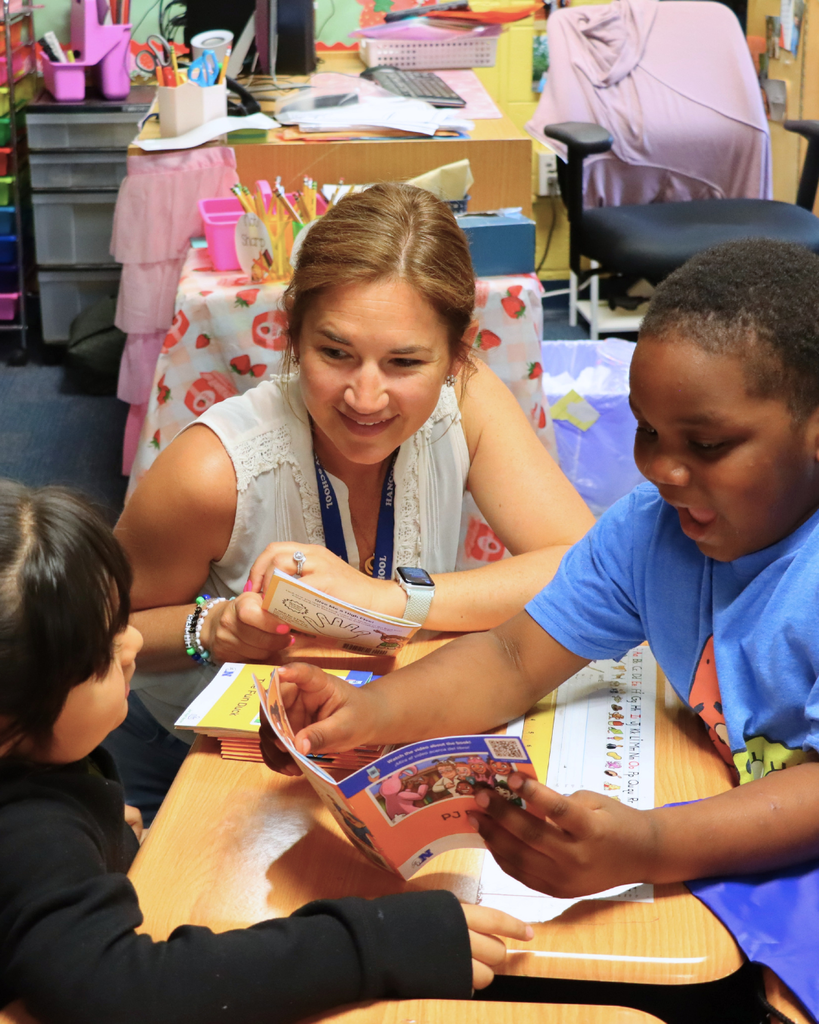 Reading specialist sitting with two students as they open their decodable books.