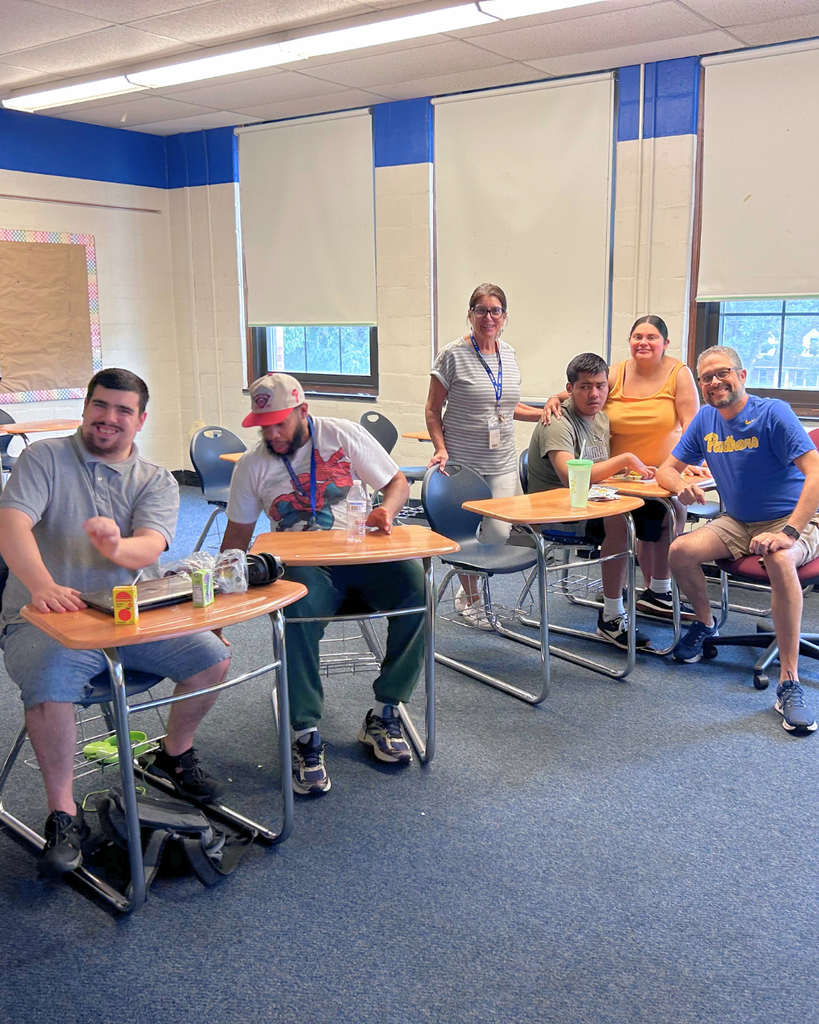 Students and staff smile for a photo in a classroom during ESY.
