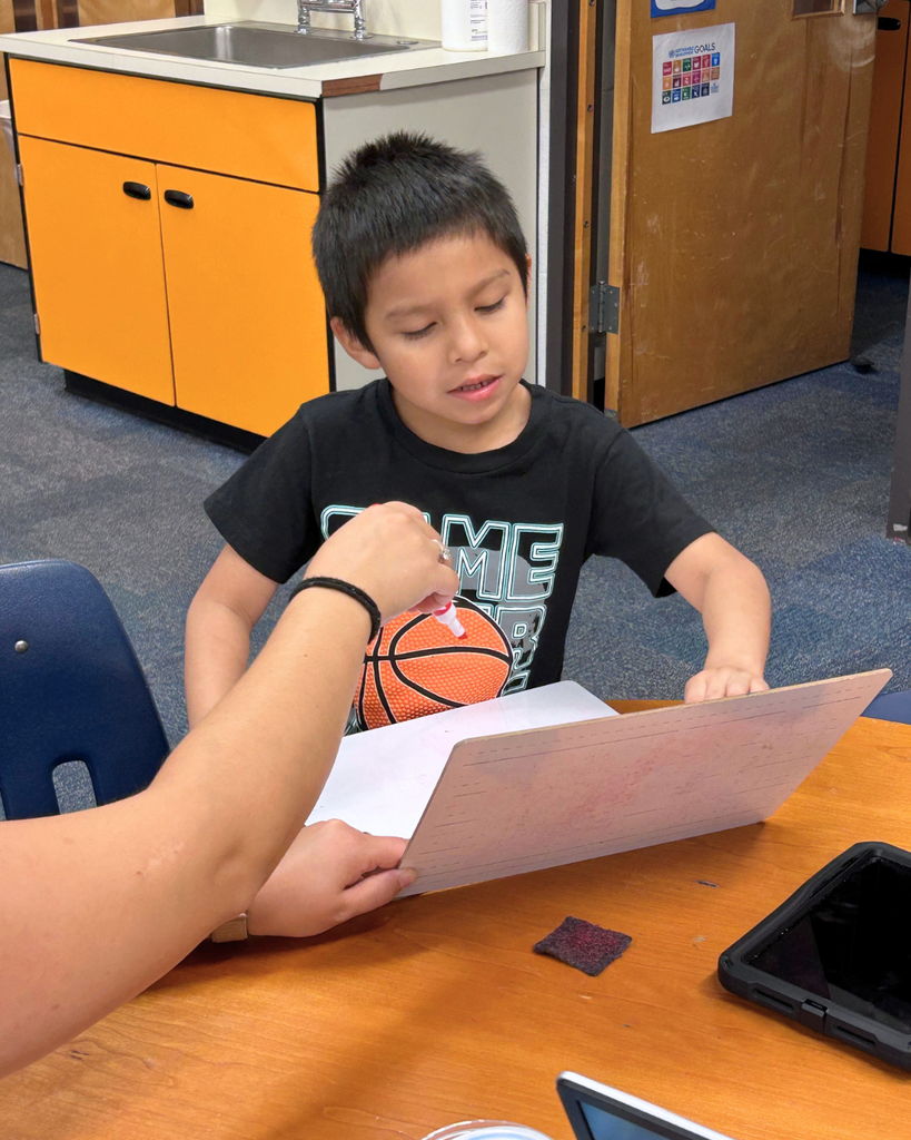 Teacher practice skills on a whiteboard with a student.