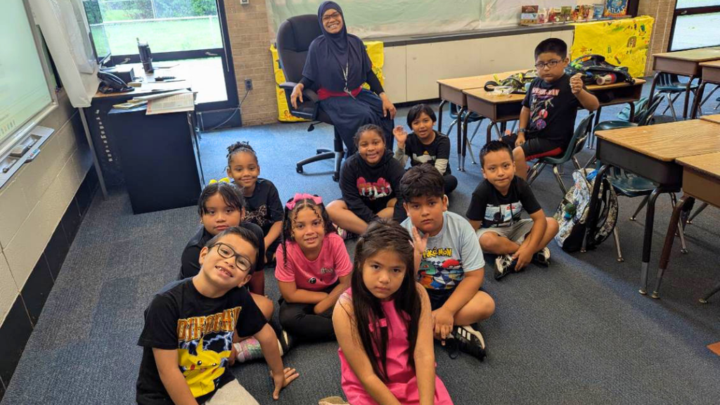 Early Literacy Summer Program classroom with students sitting on carpet.