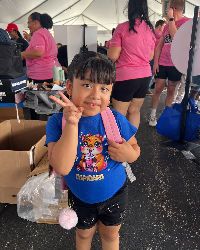 Student holding up peace sign with their new backpack.