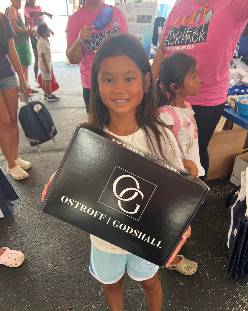 Student holding up a box from the swag table with the Ostroff Godshall logo.