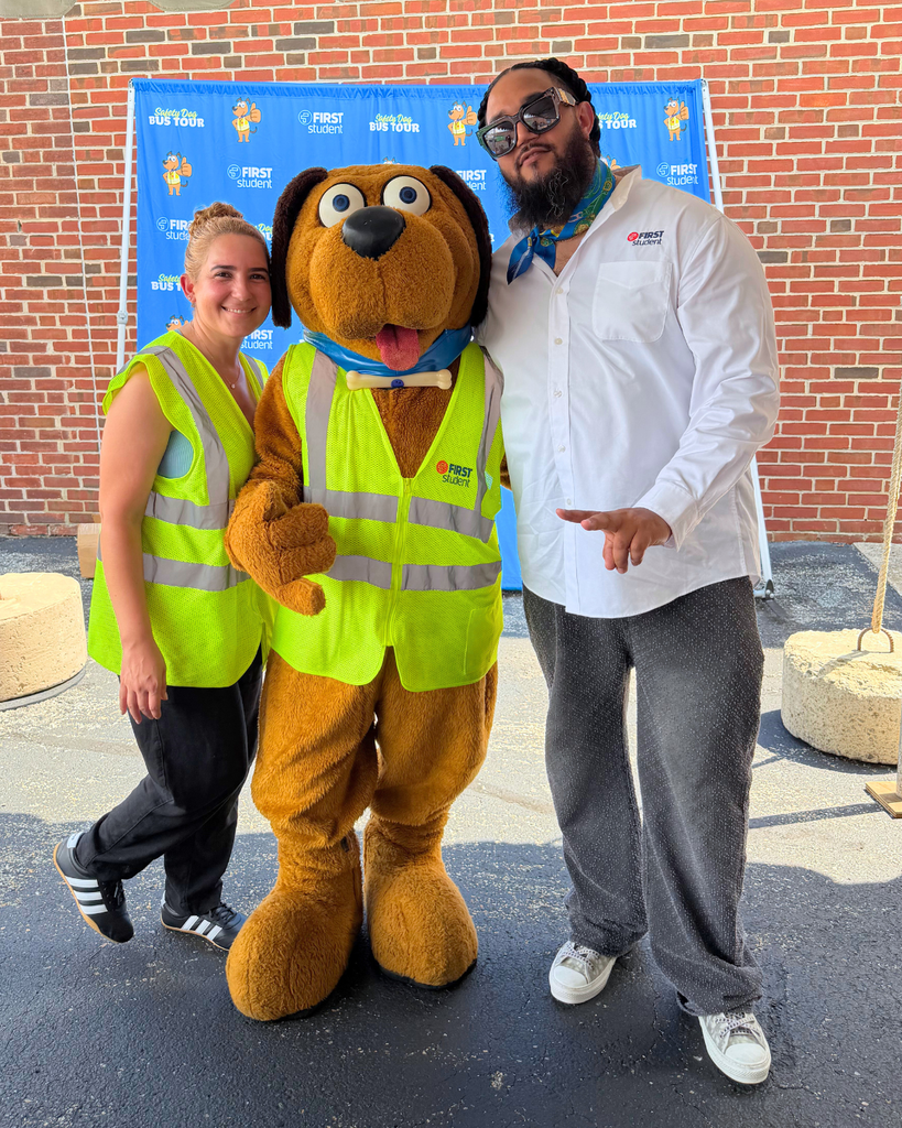 First Student Mascot, Safety Dog, poses for photo with staff members.