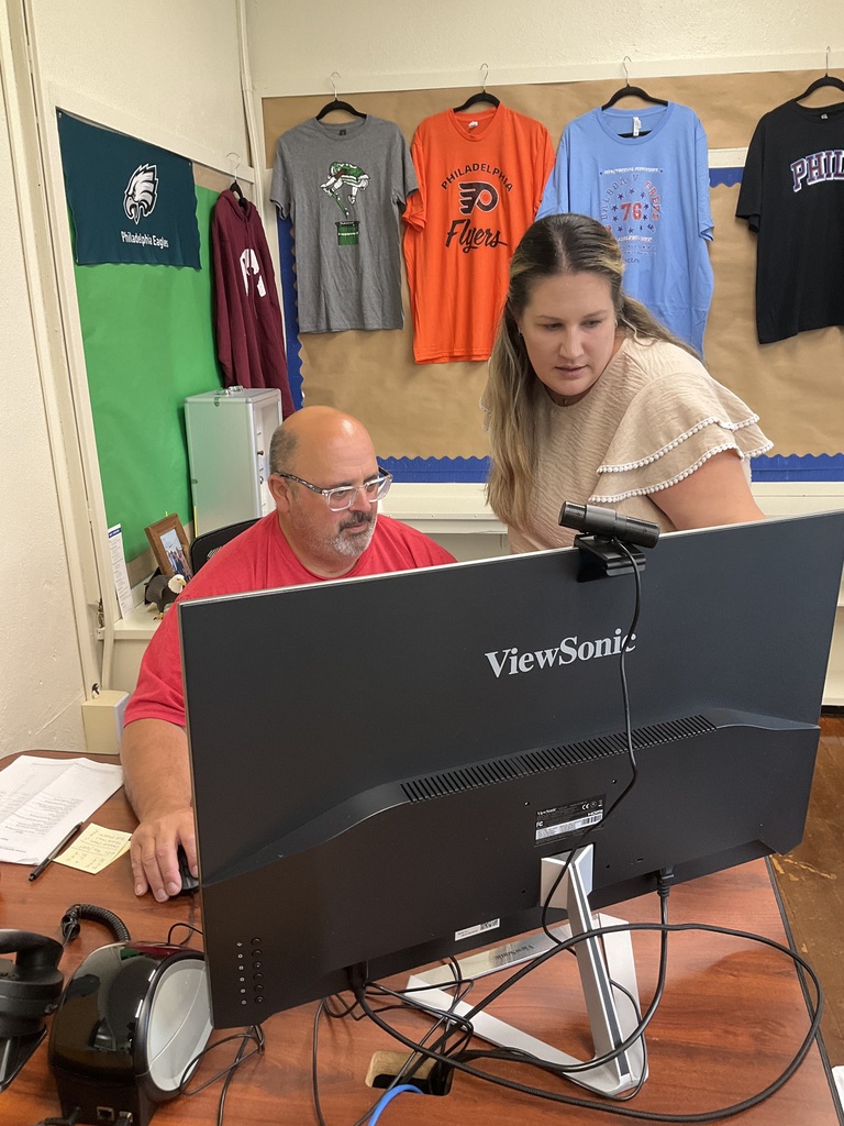 Two teachers are looking at a computer screen together