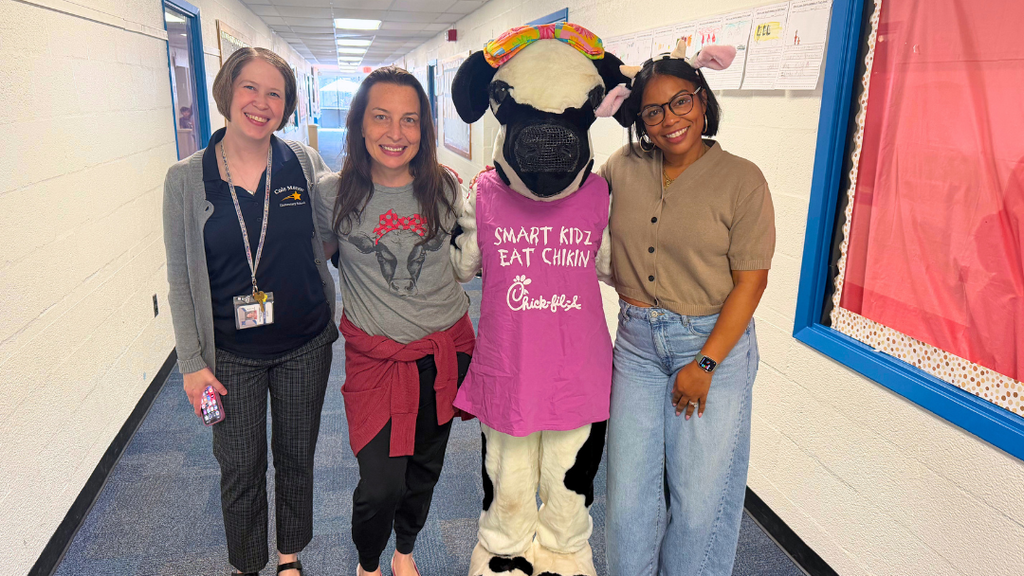 Staff stand with Chick-fil-a cow mascot.