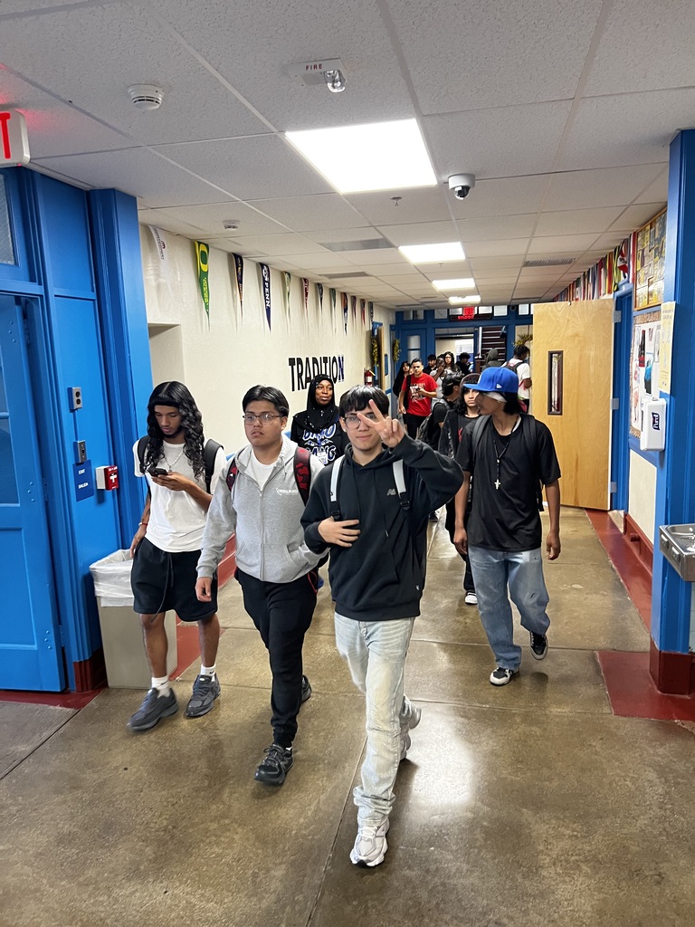 Students are walking down the hall and one is giving the peace sign
