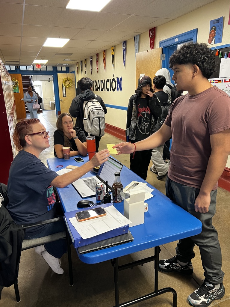 The counselor is handing a nre schedule to a student while other students are walking in the background