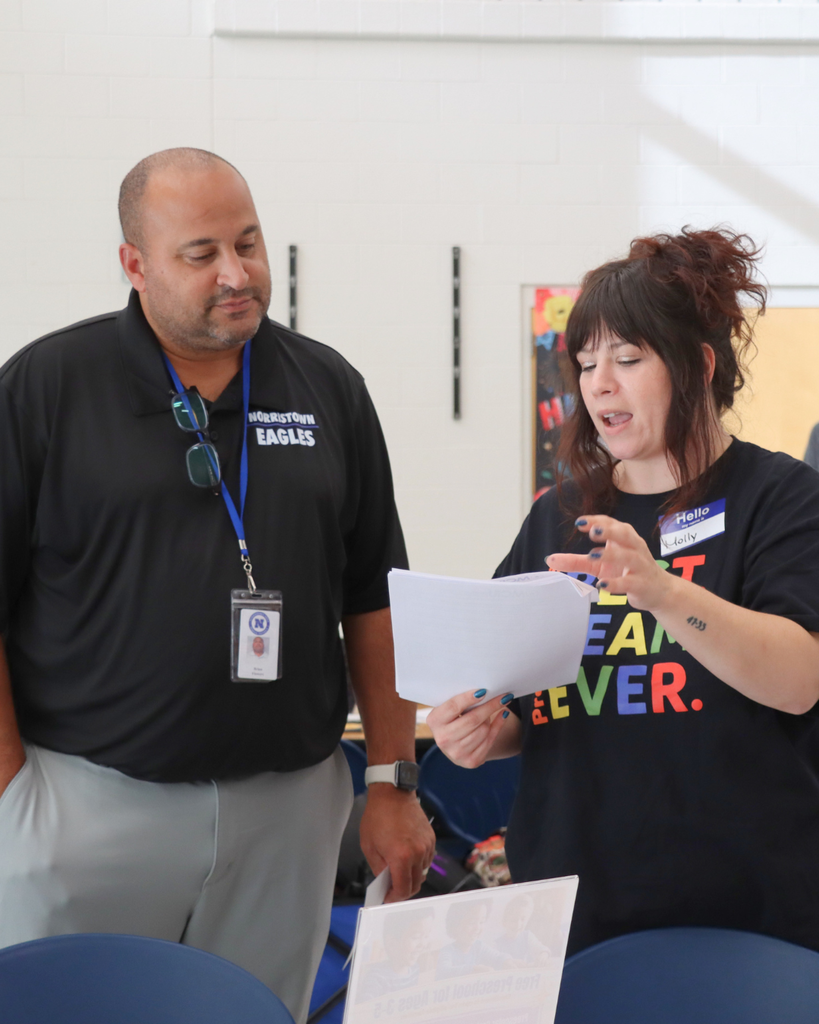Community partner speaking to a new teacher, showing them information on a piece of paper.