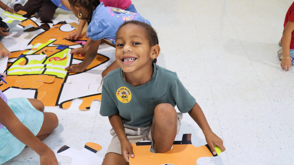 Student smiles for photo while holding puzzle piece from a Safety Dog puzzle.