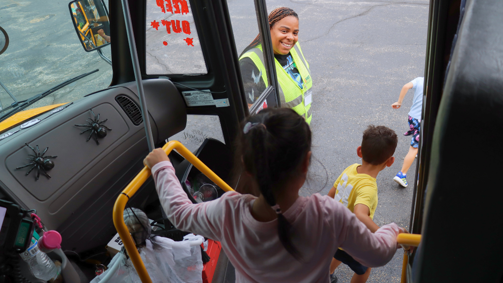 Bus driver helping student off the bus after their bus safety tour.