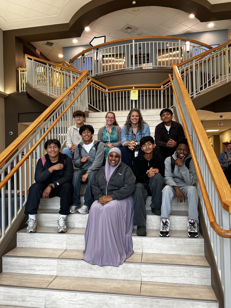Students and teachers are on a staircase posing for a picture at the MCIU