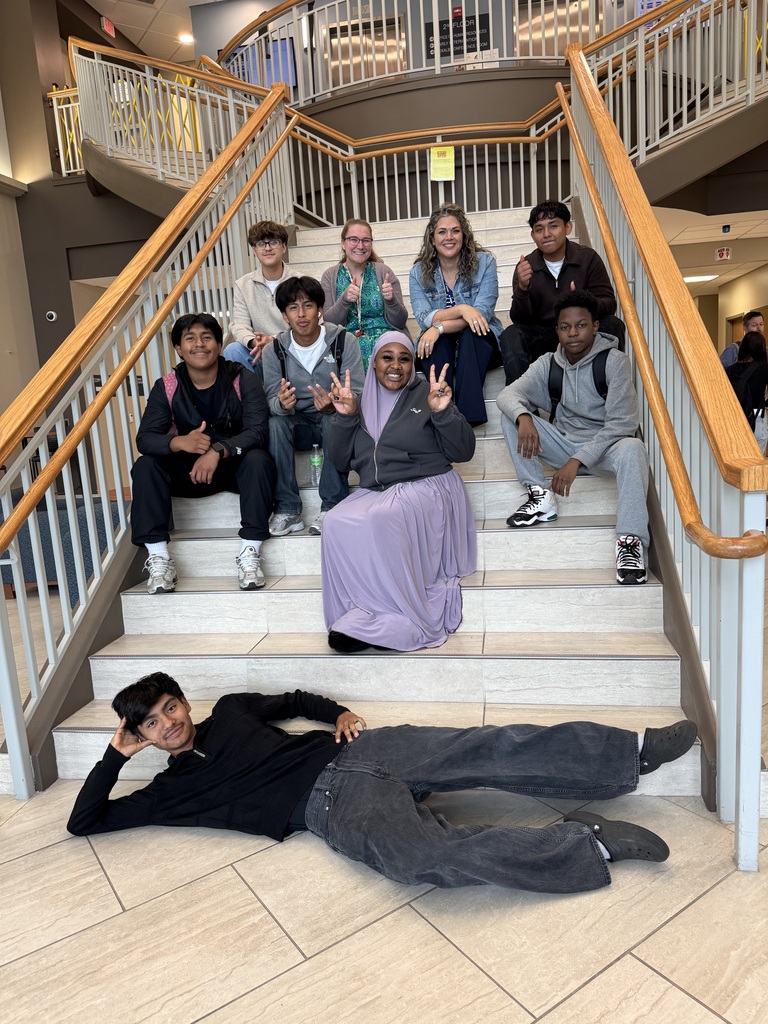 Students and teachers are on a staircase posing for a picture at the MCIU