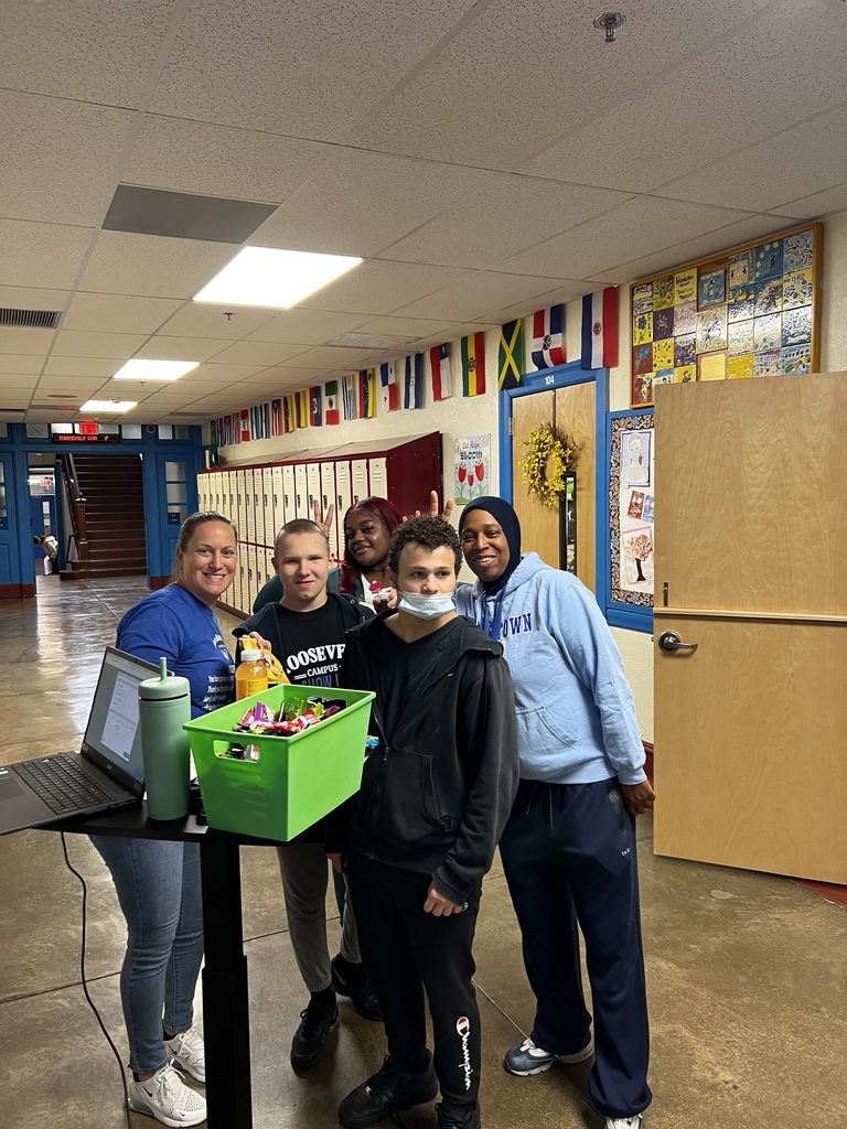 Students are posing in front of the PBIS cashout stand with some teachers.