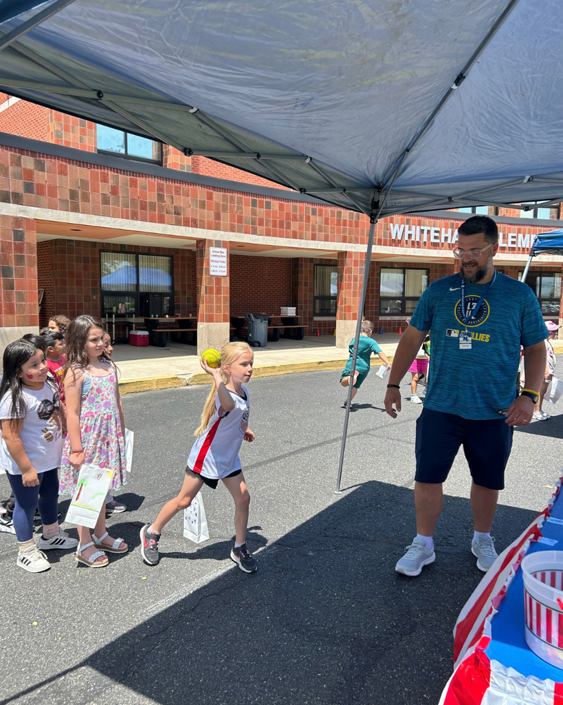 Parent volunteer helping students with a game at Whitehall's end of year carnival.