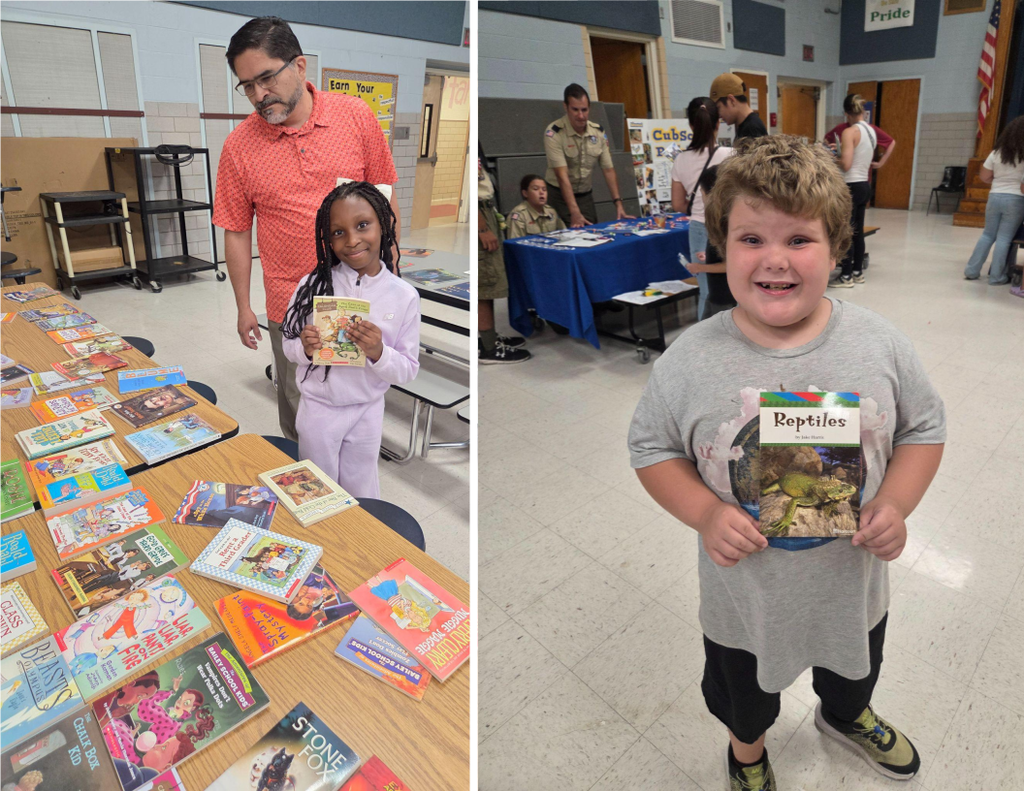Elementary school students smile as they select books during a Back-to-School Night event.