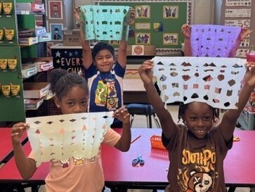 students show off their work during art class