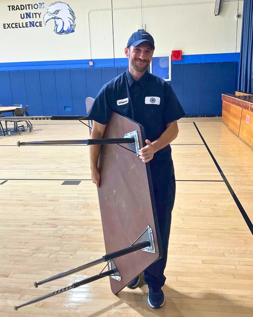 Custodian carrying a table.