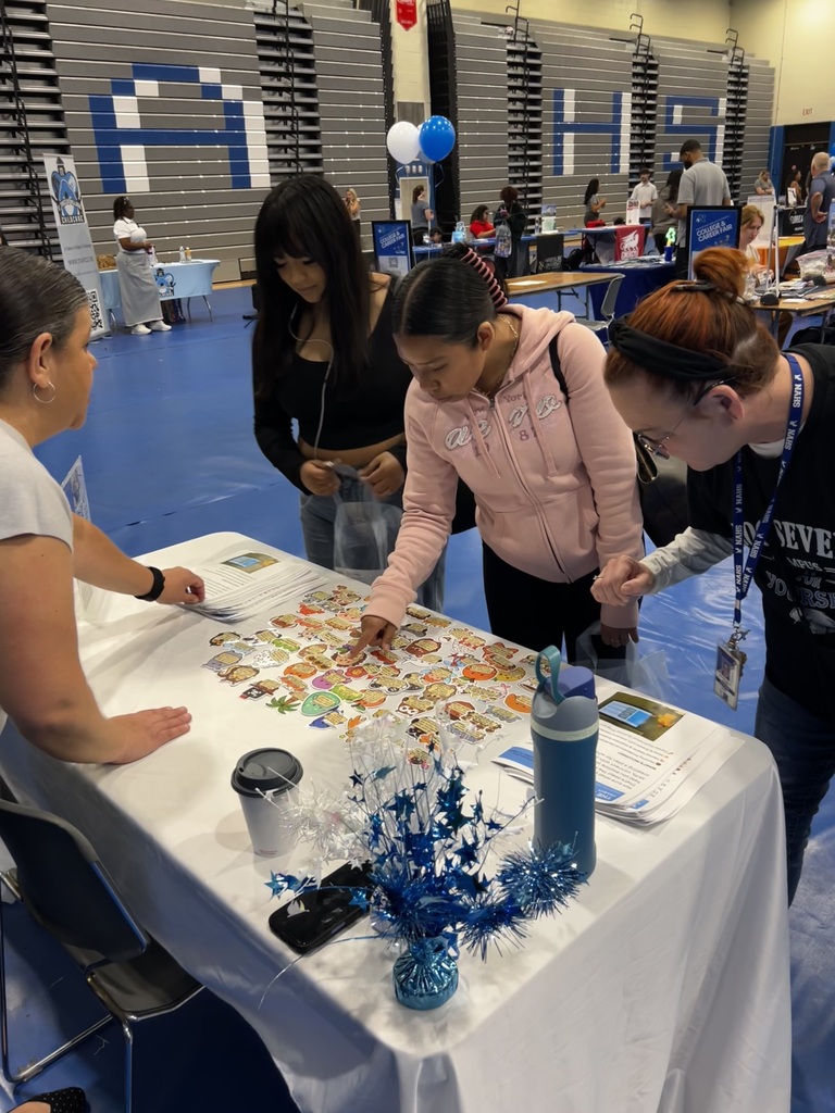 Students are gathered around a table talking to a representative