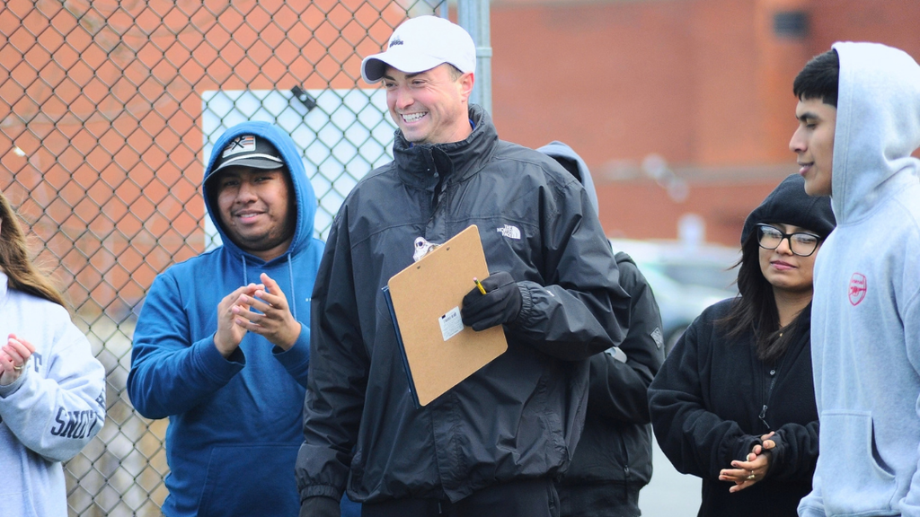 Coach holding a clip board smiling.