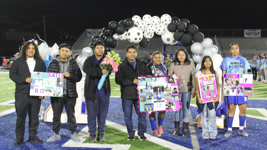 Senior athlete and family pose for photo under balloon arch.