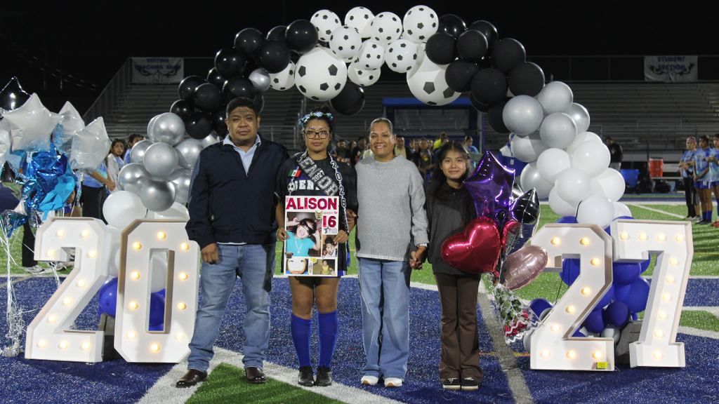 Senior athlete and family pose for photo under balloon arch.
