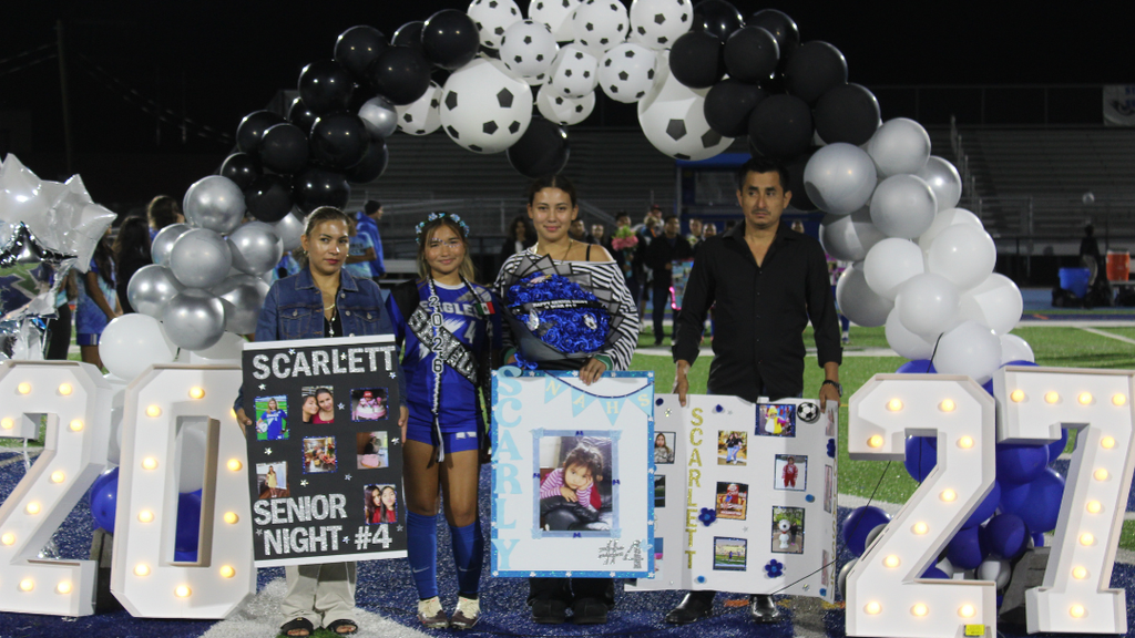 Senior athlete and family pose for photo under balloon arch.