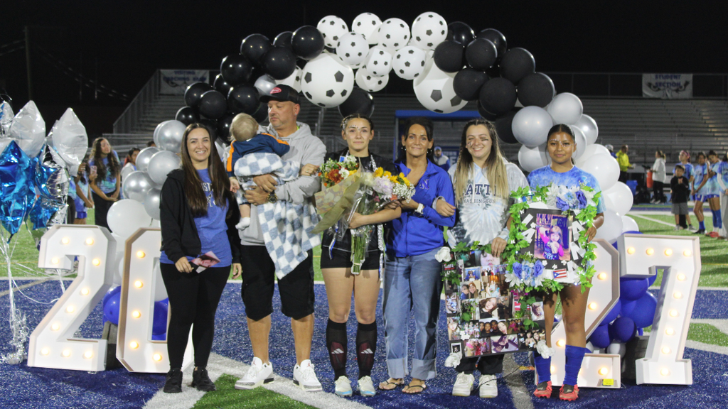Senior athlete and family pose for photo under balloon arch.
