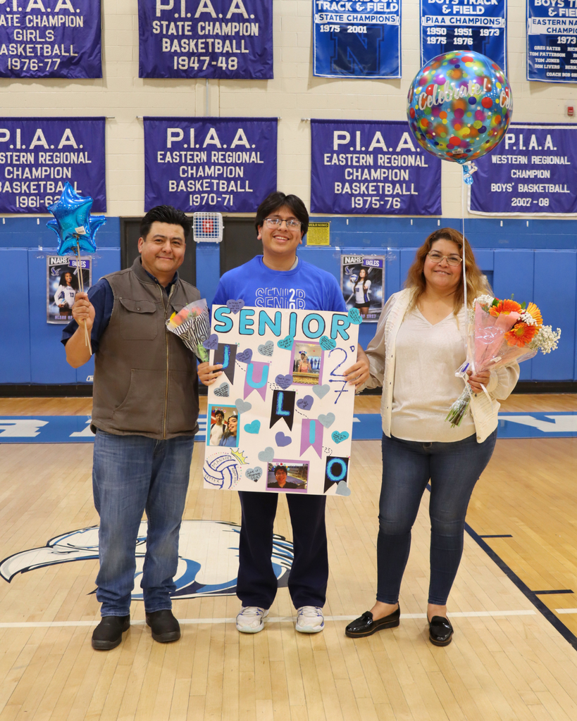 Senior athlete and family holding flowers, balloons, and poster.