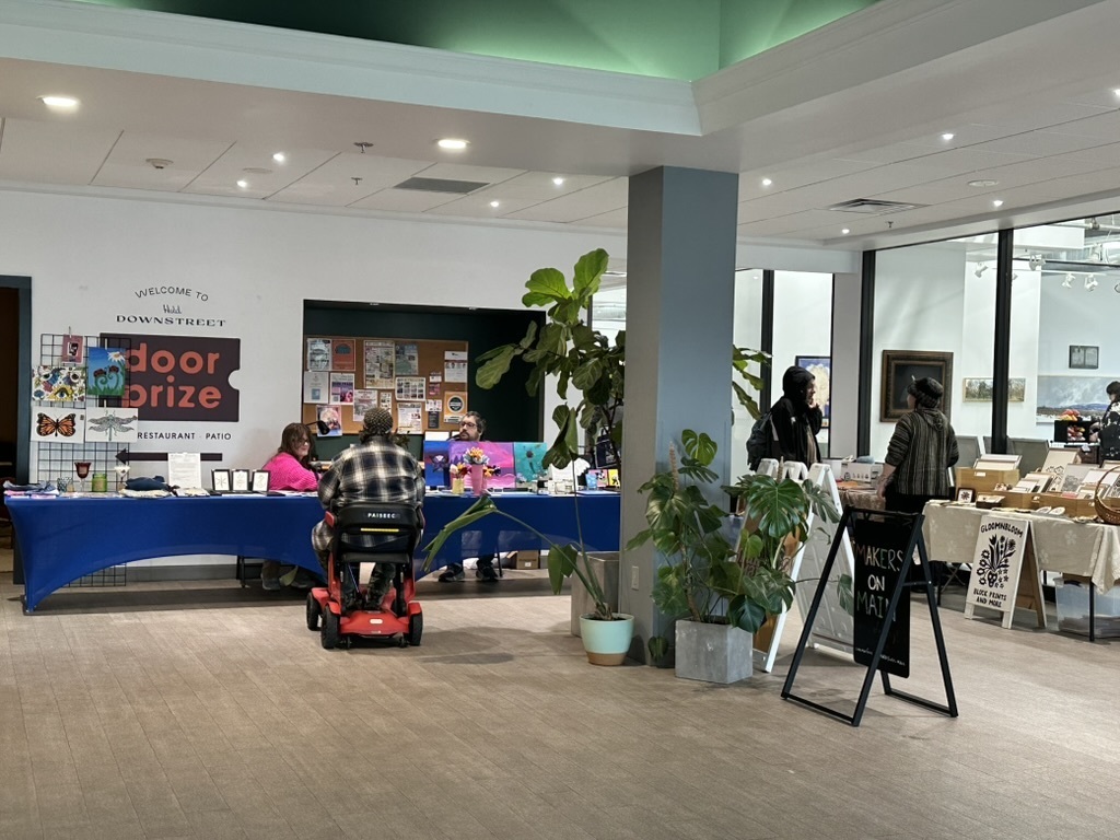 Wide photo of student art set up at art market tables
