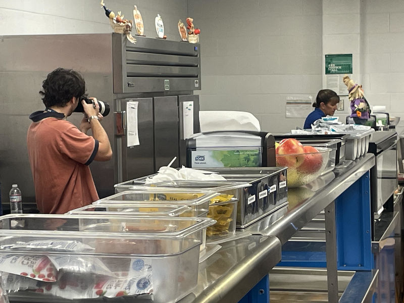 A photographer from DESE captures an employee serving lunch.