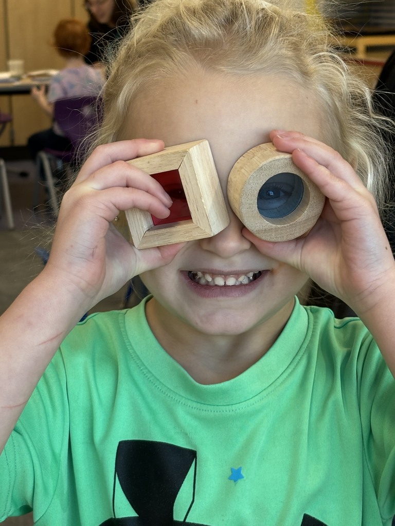 Child holding shapes to face