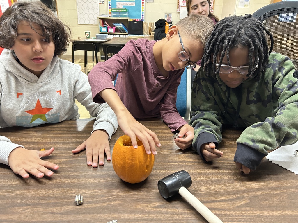 Three students are touching pumpkins.