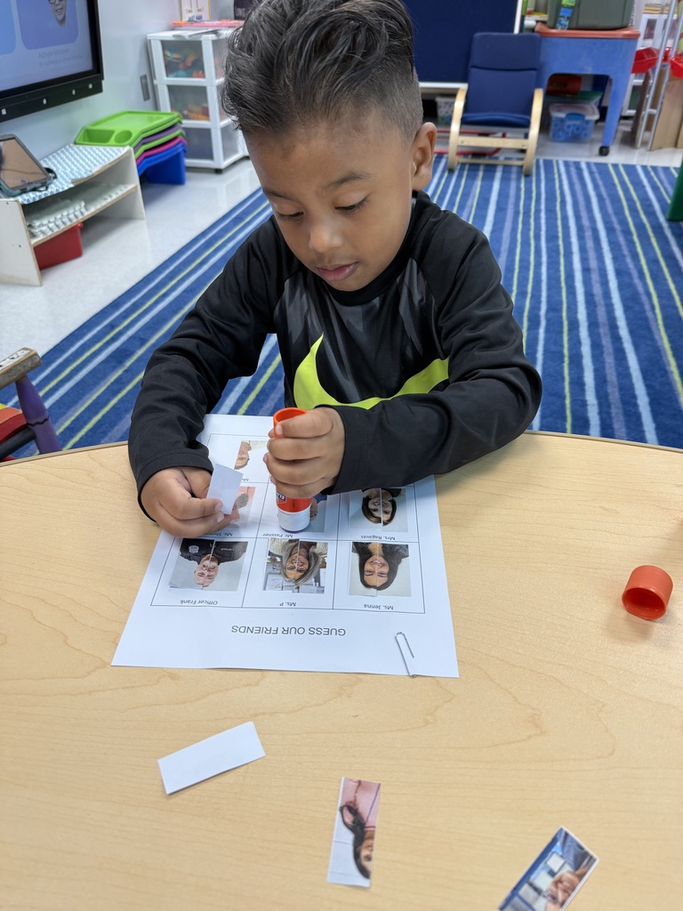 A preschool student is complete an activity where he matches the faces of important people who work in our school.