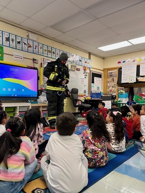 Firefighter Dave shows K-3 the order that he puts his gear on to go to an emergency.