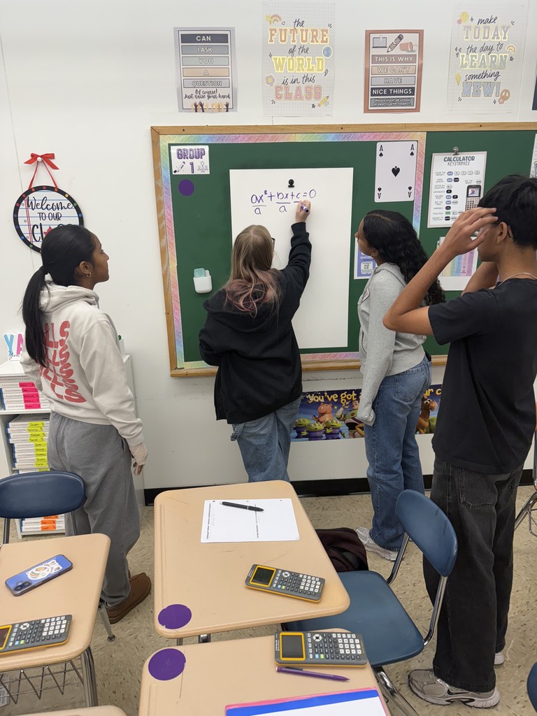Students deriving the quadratic formula in groups at whiteboards