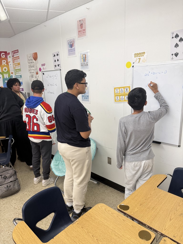 Students deriving the quadratic formula in groups at whiteboards
