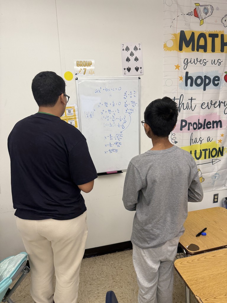Students deriving the quadratic formula in groups at whiteboards