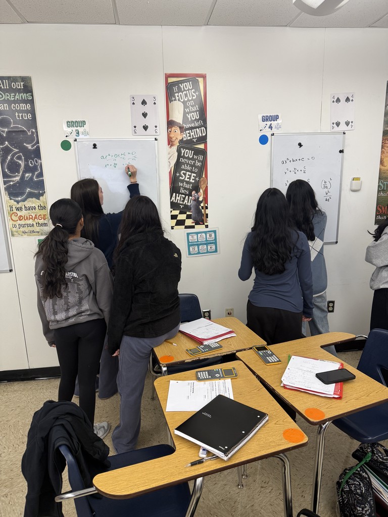 Students deriving the quadratic formula in groups at whiteboards