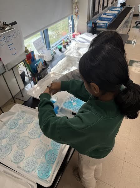 Students creating salt-crystal snowflakes out of a saturated salt-water solution.
