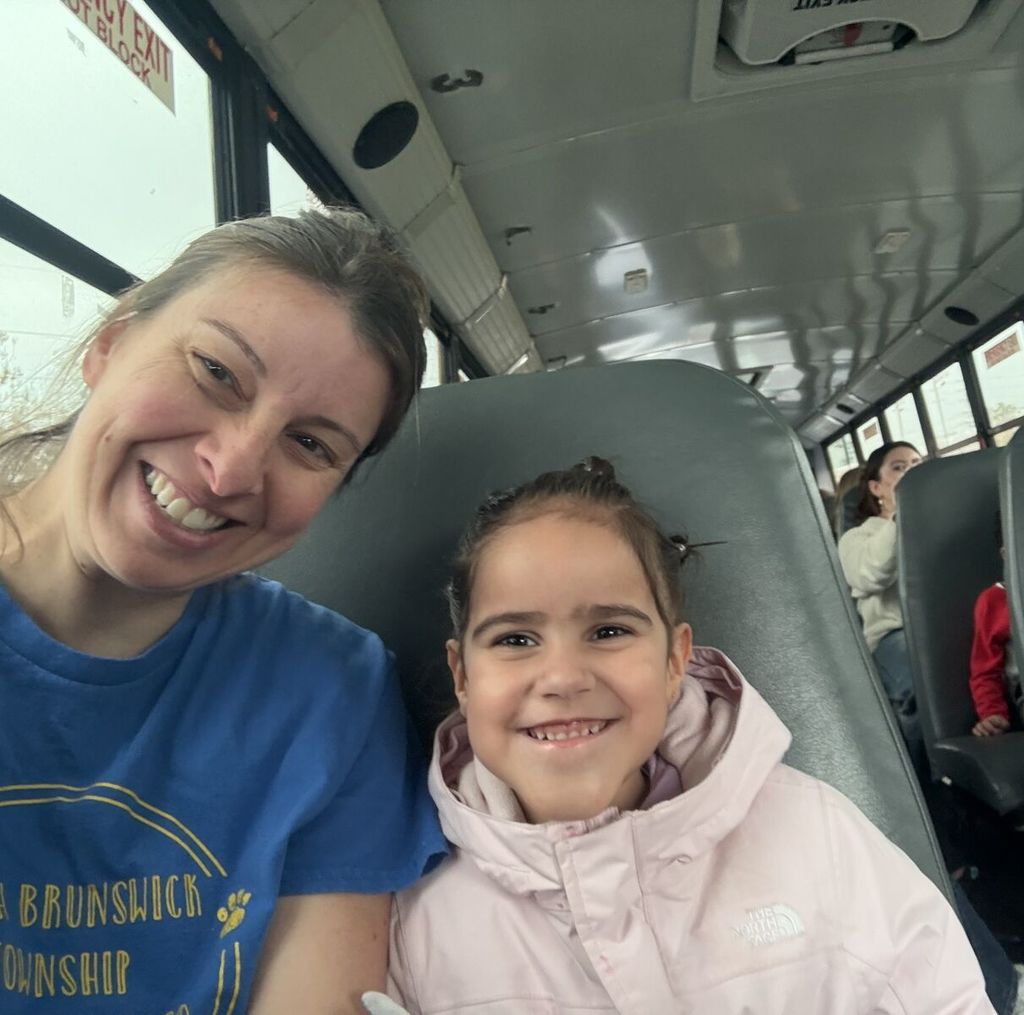 teacher and a student smile widely while riding the bus