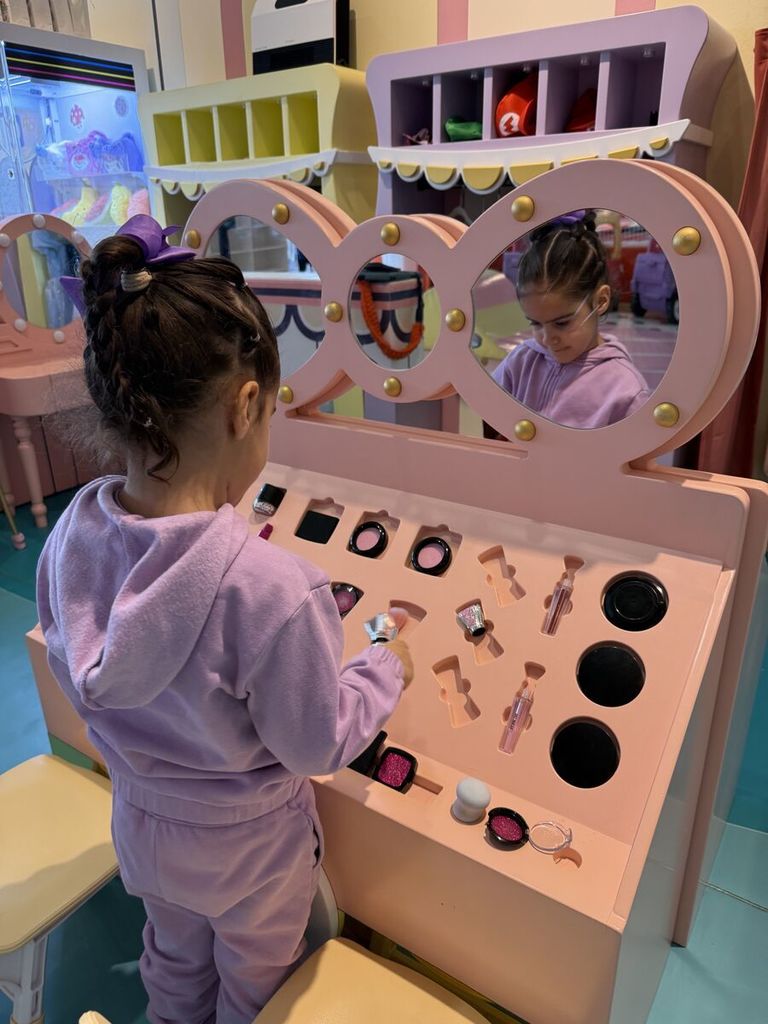 a girl plays with pretend make up in front of a mirror