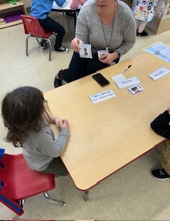 Teacher showing a "sit safely in our chairs" card to a child