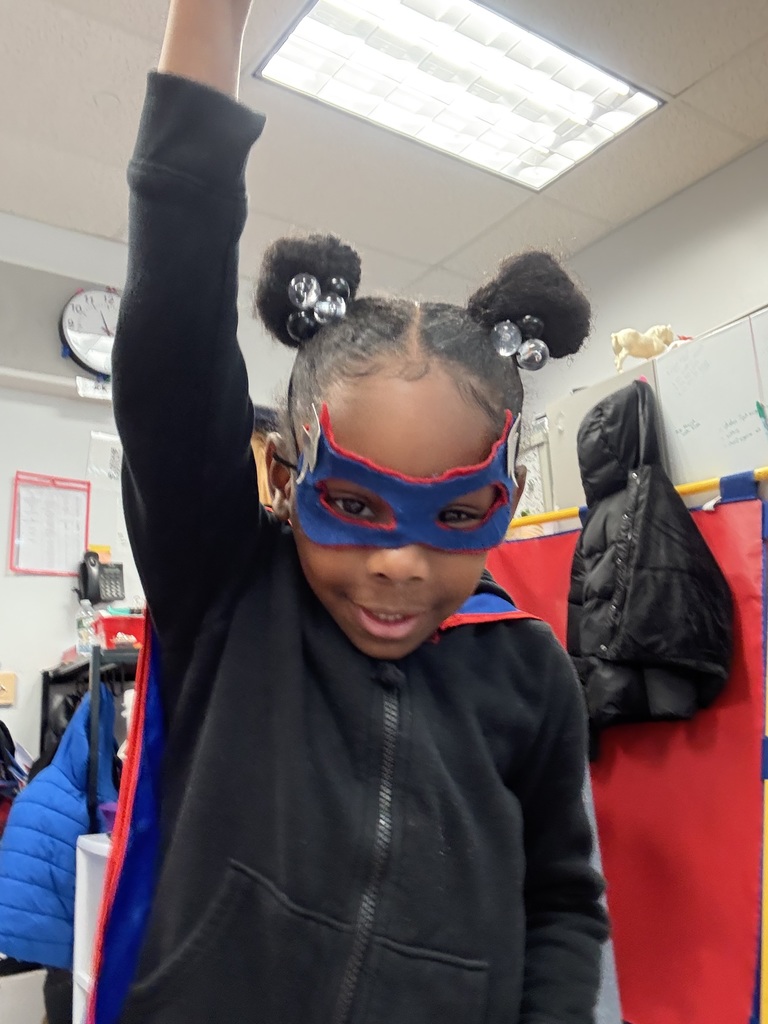 Preschool student poses as a super hero in a cape and mask