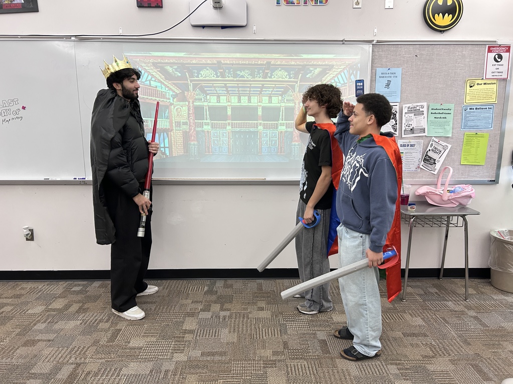 Two high school students in costume, playing Iago and Cassio, salute their general, Othello.