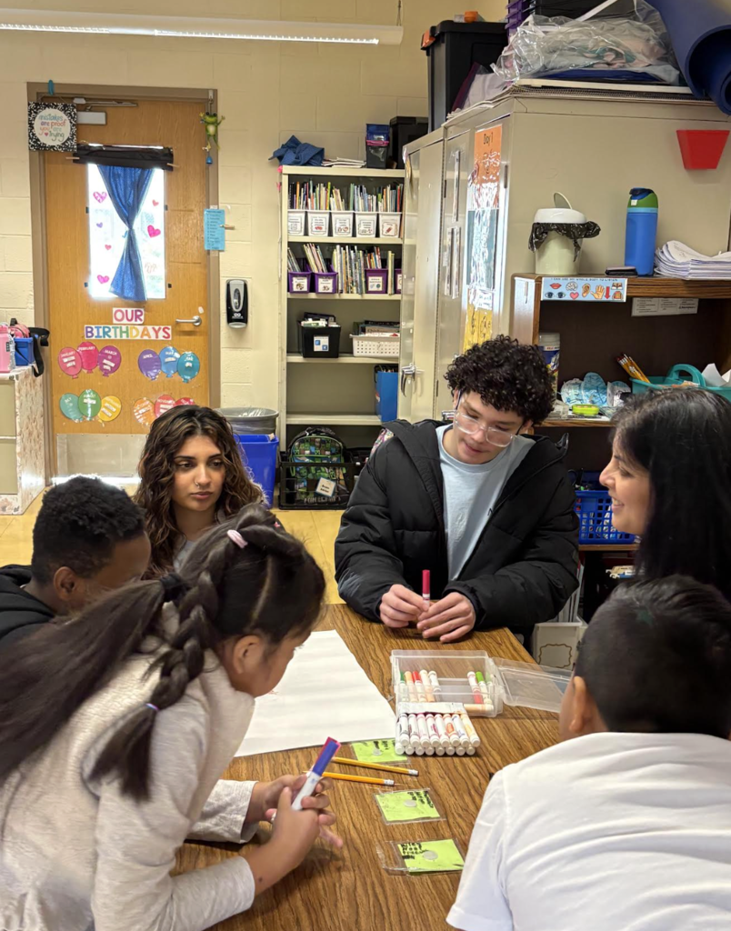 Elementary students making posters with high school helpers