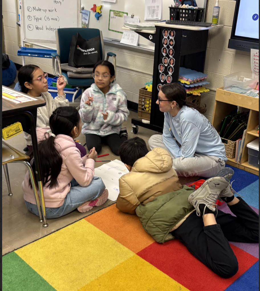 Elementary students making posters with high school helpers