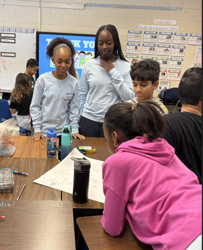 Elementary students making posters with high school helpers