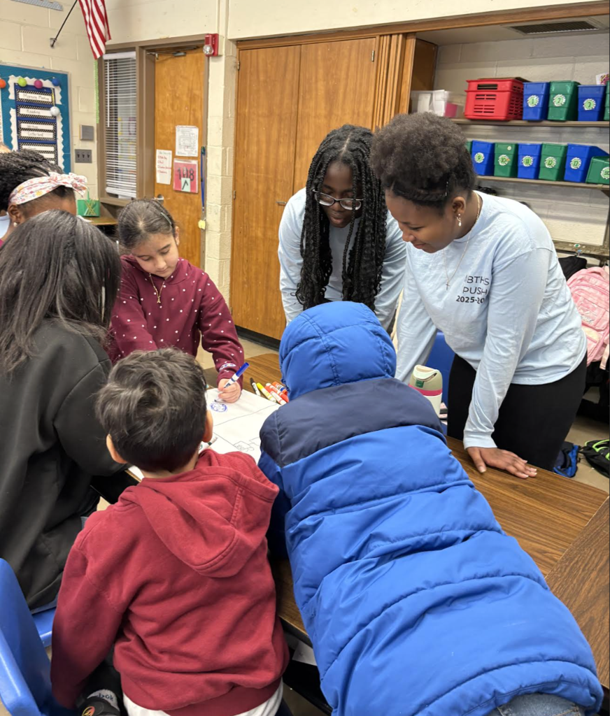 Elementary students making posters with high school helpers